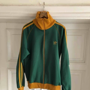  - Vintage adidas by descente Japan i grönt och senapsgul i trevligt skick. Två mindre fläckar som sannolikt går att få bort samt en söm som har fått upp i fodret lätt fixat! Ser mycket bättre ut IRL kan hämtas i Uppsala eller skickas mot porto