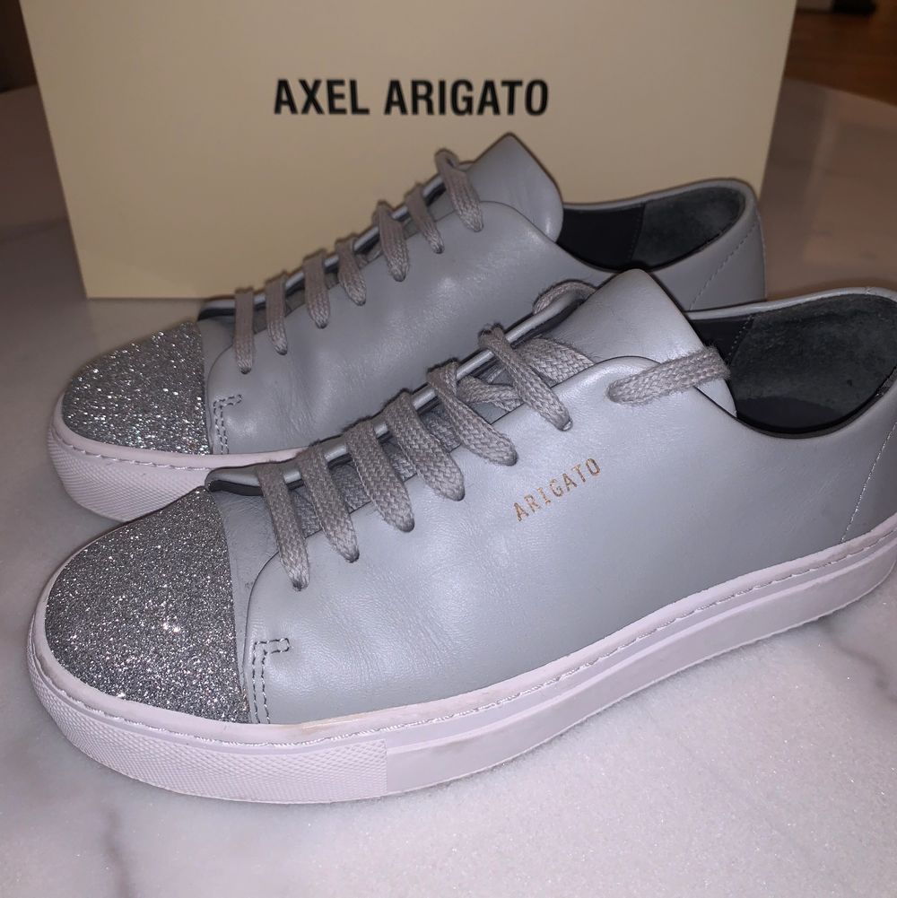 Ljusgrå sneakers från Axel Arigato med silverdetaljer längst fram. Storlek 37! Använda 1-2 ggr. . Skor.