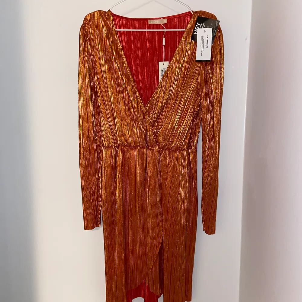 Oanvänd orange/guldig klänning från ”NLY Eve” som fortfarande har lapparna kvar. Orginalpris är 499 kr.. Klänningar.