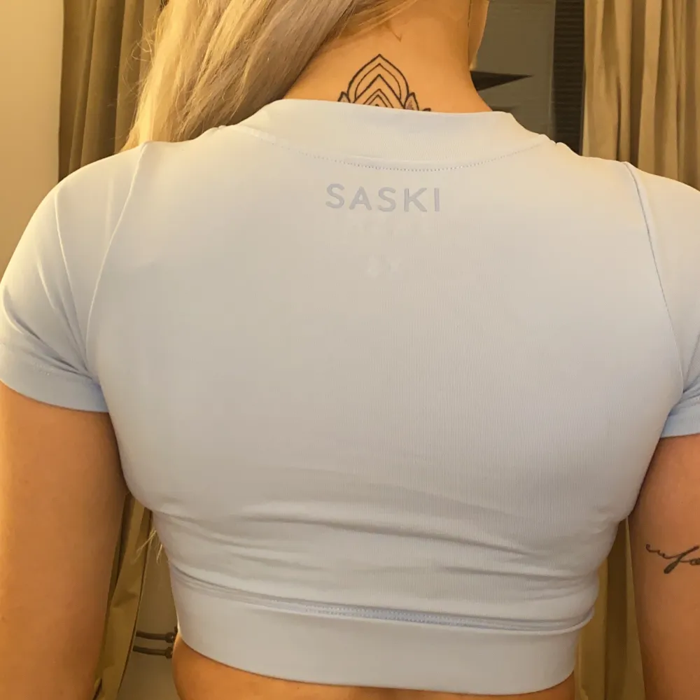 En skitsnygg ljusblå croppad träningst-shirt från Saski - Tammy Hembrows sportmärke. Använd en gång och säljer då den sitter aningen tight på mig. Passar XS främst och sitter såhär på mig som är storlek S.. T-shirts.