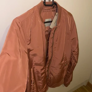 Skitsnygg bomberjacka med en härlig färg!!  - En super snygg bomberjacka som är helt ny (prislappen kvar). Med en härlig rosa aktig färg på sig. 