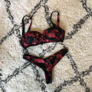 NAKD hannalicous bikini!  - Ros bikini med svart grund. Storlek S i nederdel och XS i överdel. Toppen är endast använd en gång och underdelen är använd 2-3 gånger. Köparen står för frakten.