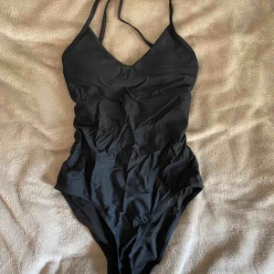  - Svart basic baddräkt i strl S. Framhäver kurvorna på ett väldigt smickrande sätt. Lägg märke till banden på ryggen😍 Vadderad! Använd endast 1 gång och såklart tvättad. Köparen står för 🚚.
