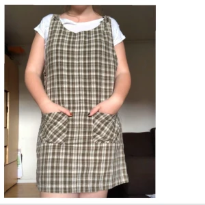 Rutig hängselklänning  - Säljer denna underbara hängselklänning köpt på beyond retro då jag inte använder tillräckligt ofta. Den har två fickor fram och har två knappar att reglera längden med ❤