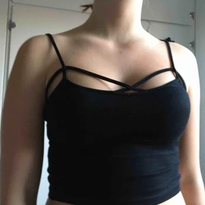  - Svart linne med fina detaljer, det är en magtröja som slutar ungefär ovanför naveln