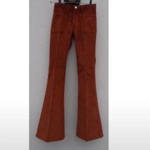  - Helt nya utsvängda manschsterjeans av märket Wrangler från 70-talet stl W27.Midjemåttet runtom är 69 cm och måttet från midjan fram - grensömmen är det 23 cm.Stussmåttet från sida - sida är 41 cm. Längden på jeansen från midjan fram och ned är det 96 cm.Materialet i jeansen är 100% bomull.  Kolla måtten noga 🌻. Köparen betalar frakten. 