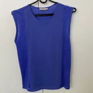 Säljer denna blå tröja utan ärmar från Calvin Klein Jeans. Väldigt fin och skön att bära under sommaren då materialet vid ärmarna och sidorna består av 100% linne medan tyget på framsidans mitt är gjord av en blandning av chiffon och polyester. 