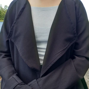 Svart kappa - Svart kappa i bra kvalité. ✨ Plagget är väldigt rörligt och har två stora fickor samt ett bälte som går att koppla bort.