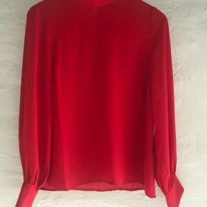 Röd blus  - Denna blus är en lose fit med hög krage från Gina Tricot. Knappt använd och därför i mycket bra skick. 