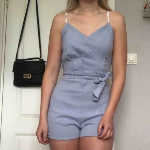  - Shorts jumpsuit i randig vit och ljusblå. Finns ett snöre att knyta runtom midjan hur man vill. Använd 1 gång, finns inlägg. Bara att höra av sig vid frågor!🍀   Ps. Snabb affär = ingen frakt