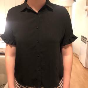 Svart, kortärmad skjorta från Therese Lindgrens kollektion med NA-KD. Använd en gång så i bra skick! Relaxed fit och enkel att styla!