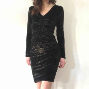  - Festklänning i svart sammet och guldtryck. Rynk mitt fram, i sidorna och på ärmsluten. Använd 1 gång för länge sen. Strl 10 = 38 men rätt pluttig sådan.  Betalning sker med swish. Köparen står för frakt. Kan annars hämtas upp i Hökarängen. ✨ 