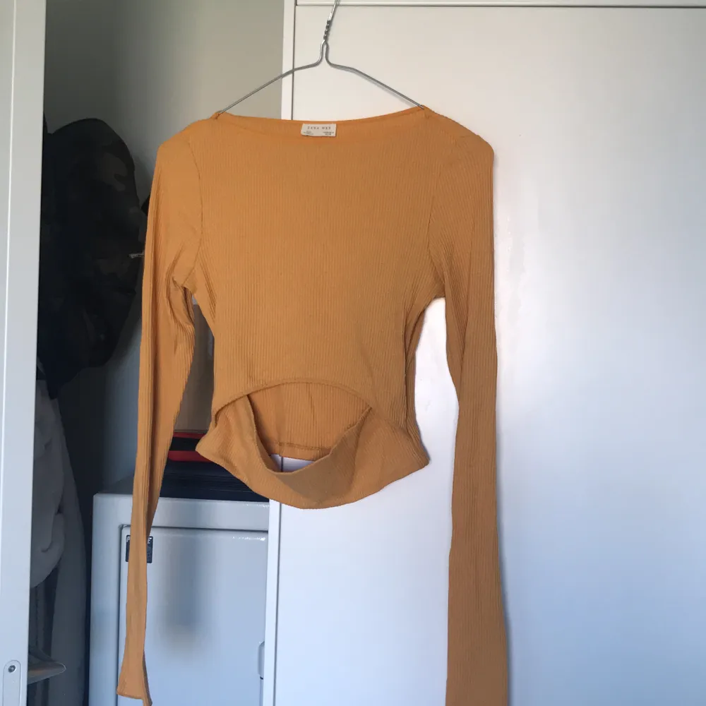 Gul/orange tröja (svårt att få till korrekt färg) med öppning på magen. Några år gammal, bra skick. Tar inga fler bilder än de som finns. Frakten ingår i priset. Toppar.