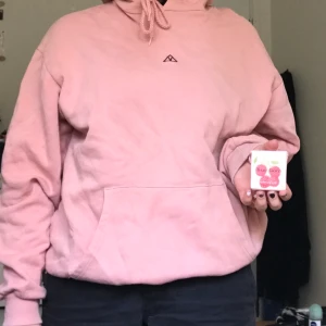 rosa hoodie - jättesnygg rosa hoodie, superbekväm och lagom tjock. den har typ en lila/vinröd broderad triangel med ett V innuti på framsidan. 