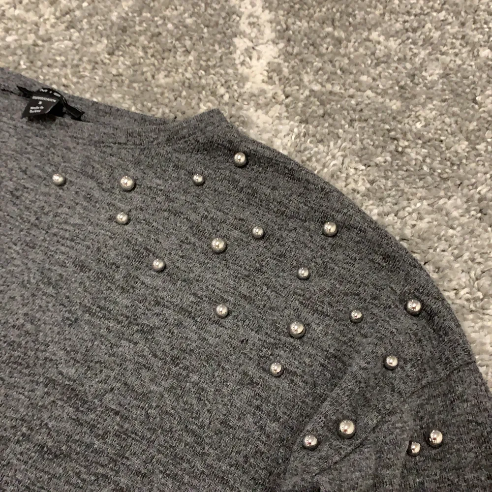 Grå långärmad tröja med små silvriga kulor på ärmarna. En snygg detalj! . Tröjor & Koftor.