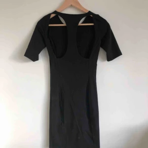  - Svart tight klänning med utskuren rygg.  3/4 ärm gjord i bomull