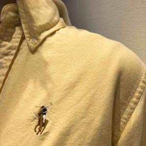  - Snygg gul Ralph Lauren skjorta i linnetyg. Lätt att styla och väldigt skön på! 