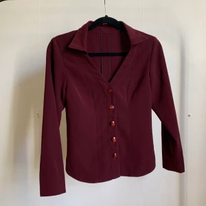 Vinröd skjorta med glittriga knappar  - Vinröd skjorta med jättefina glittriga knappar. Saknar lapp (2d hand) så okänt märke och storlek men passar en S-M.  Köparen står för frakt men kan mötas i Stockholm! ✨