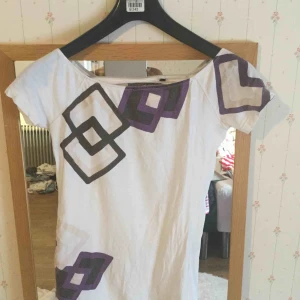  - en beige T-shirt med ett hål bakom.