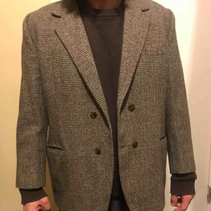  - Harethorn Tweed 100% ull svartgrått, ljusgrått, mellangrått, grönt diskret rutigt Passar 160-170cm med större mage Över axlarna som stl.48-50 (jag väger 68kg) 108cm över magen Falskt dubbelknäppt, kan sprättas bort