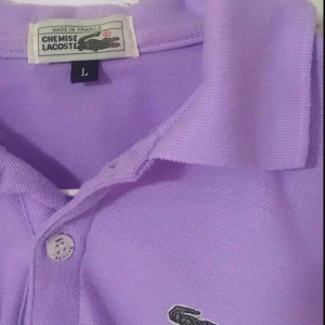  - violett piké från märket lacoste. köpt second hand, men i gott skick. frakt 50 kr eller mötas upp i stockholm. <3
