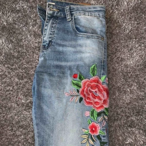  - Ett par superfina och sköna jeans med blommor på ena benet. Dem är stretchiga. Säljer för att dom är för små vid höfterna, den enda defekten är att ett fäste har gått sönder men det är nog lättlagat. Kan fraktas