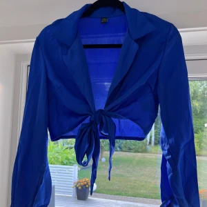 Blå blus - En blå blus med silkigt material. Säljer pga att den aldrig kommit till användning. Luftig och skön med tunt tyg. Passar perfekt till utekvällen! Lite mindre i storleken, den passar mig som har S 😊🙌🏻  (ALDRIG ANVÄND)  Längd: 41 cm Axel: 40 cm