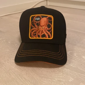 Capslab keps Eight  - Äkta capslab keps. Helt oanvänd. Truckerkeps med detaljer av orange. Ny pris är 500.  Skriv Järna om du är intresserad i kepsen.