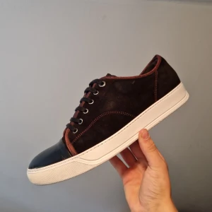 Lanvin Cap-toe Burgundy - Säljer ett par snygga röda lanvin cap toe med svarta detaljer och vit sula. Skorna har en stilren design med snörning och är perfekta för vardagsbruk. De är i bra skick och kommer med originalkartong.