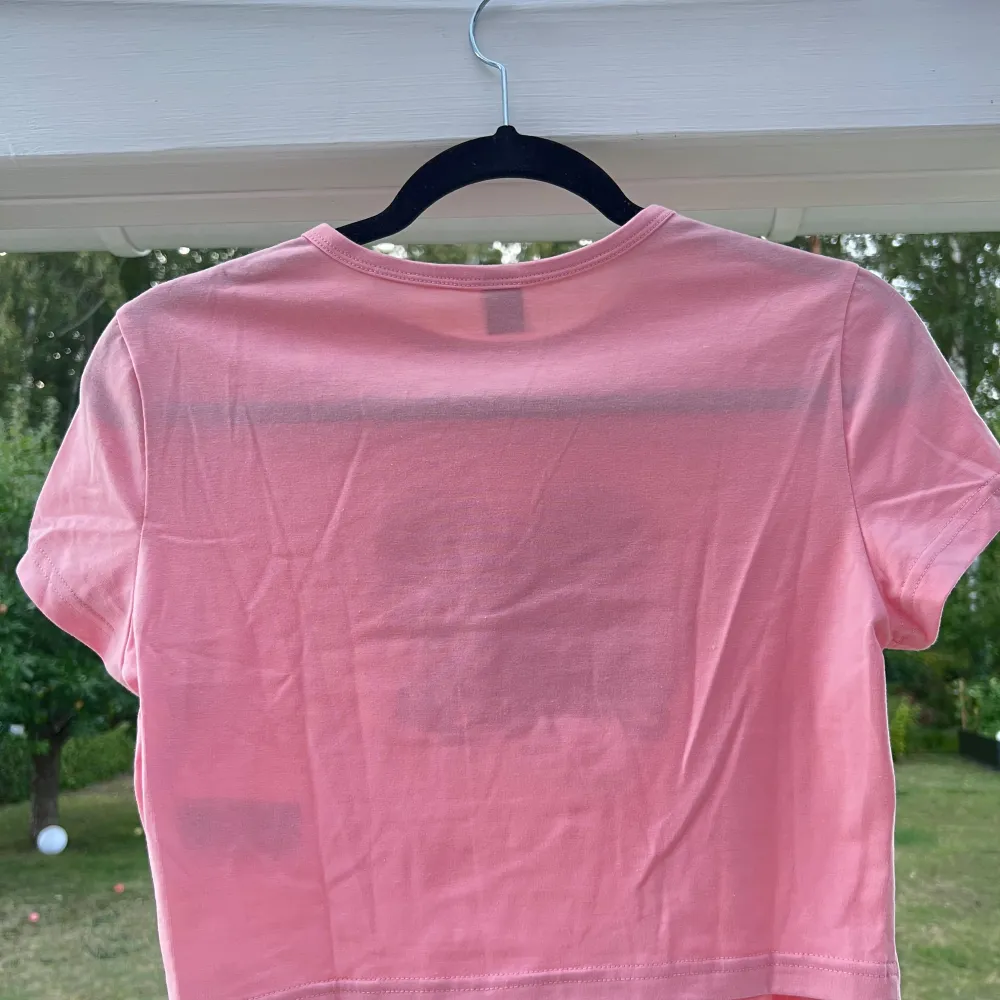 Croppad rosa t-shirt med gulligt katt-tryck 🐱💞 Aldrig använd så det är därför jag säljer den! Liten i storleken då jag själv bär S 🥰  (ALDRIG ANVÄND)  Längd: 44 cm Axel: 39 cm. T-shirts.