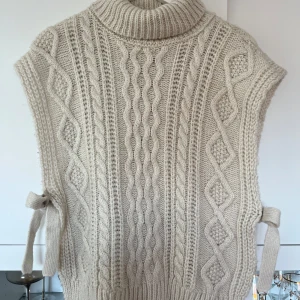 Stickad Väst - Säljer en beige, stickad väst med snörningsdetalj på sidorna. Mycket bra skick! Vet inte exakt vart den är köpt, skulle gissa Only/Vero Moda. 