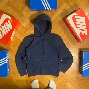 Blå hoodie från Peak Performance - Säljer en snygg blå hoodie från Peak Performance. Den har en dragkedja framtill och en justerbar huva med snören. Perfekt för en avslappnad stil och passar bra till både vardag och träning. Storlek Medium 