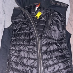 Svart väst från Parajumpers (passar M-L) - Säljer en snygg och varm svart dunväst från Parajumpers. Västen har en dragkedja framtill och är quiltad för extra stil och värme. Perfekt för höst och vår när du vill hålla dig varm. Den är i storlek XL och i nyskick. Passar folk som använder M-L.