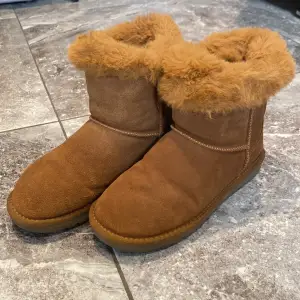 Säljer ett par mysiga bruna Ugg med fluffigt pälsfoder. Perfekta för kalla dagar! De är i mycket bra skick, är inte så mycket använda och har en robust sula som ger bra grepp. Superbekväma och håller fötterna varma hela vintern. Märket är inte ugg utan Duffy men ser verkligen ut som ugg. pälsen går att stoppa in i skon om man hellre föredrar att ha det så:) 