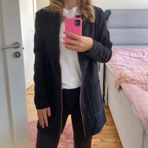 Svart kavaj från Lady Blush - Säljer en elegant svart kavaj från Lady Blush. Den har en snygg dragkedja framtill och två praktiska fickor. Perfekt för både vardag och fest! Materialet är spets likande. 