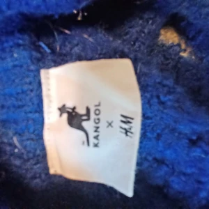 Stickad kangol tröja - Denna stickade tröja är i storlek XS fast är jätte stor i storleken. Tröjan känns som en XL och kan tämjas ut väldigt enkelt den är 5-färgig som man kan se på bilden. Tröjan har ett stort kangol märke nere på tröjan .färgerna finns vid taggarna.