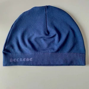 Mörkblå mössa från decrease.se - Snygg mörkblå mössa från Decrease med en enkel och stilren design. Perfekt för att hålla värmen under kyliga dagar. Passar bra till både vardag och mer avslappnade tillfällen. Inte använd bara testad, säljer för att den passade inte mig, nypris 90kr