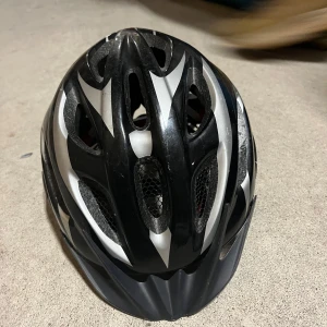 Svart och vit cykelhjälm från Giro - Snygg och säker cykelhjälm från Giro i svart och vitt med justerbara remmar och ventilerande design. Perfekt för cykelturer i alla väder. Inredningen är vadderad för extra komfort.