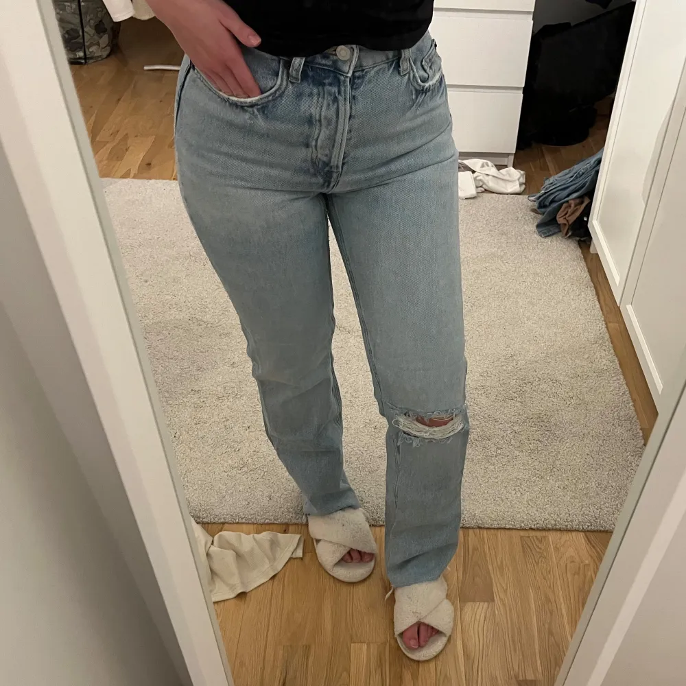 Snygga ljusblå jeans med hög midja och slitningar på knäna. De har en klassisk femficksdesign och en straight passform som ger en avslappnad look. Perfekta för en trendig vardagsstil.. Farkut & Housut.