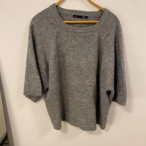 Stickad tröja - Mysig grå stickad tröja från 157 med trekvartsärmar. Perfekt för kyliga dagar och enkel att matcha med olika outfits. Tröjan har en avslappnad passform och rund halsringning.