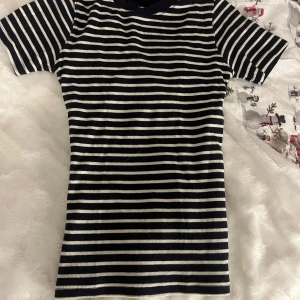 Randig kortärmad topp - Säljer en stilren randig topp i svart och vit med korta ärmar. Perfekt för en avslappnad look. Toppen har en klassisk design med rund halsringning. Storlek xxs, väldigt stor i storlek (passar S) 💕