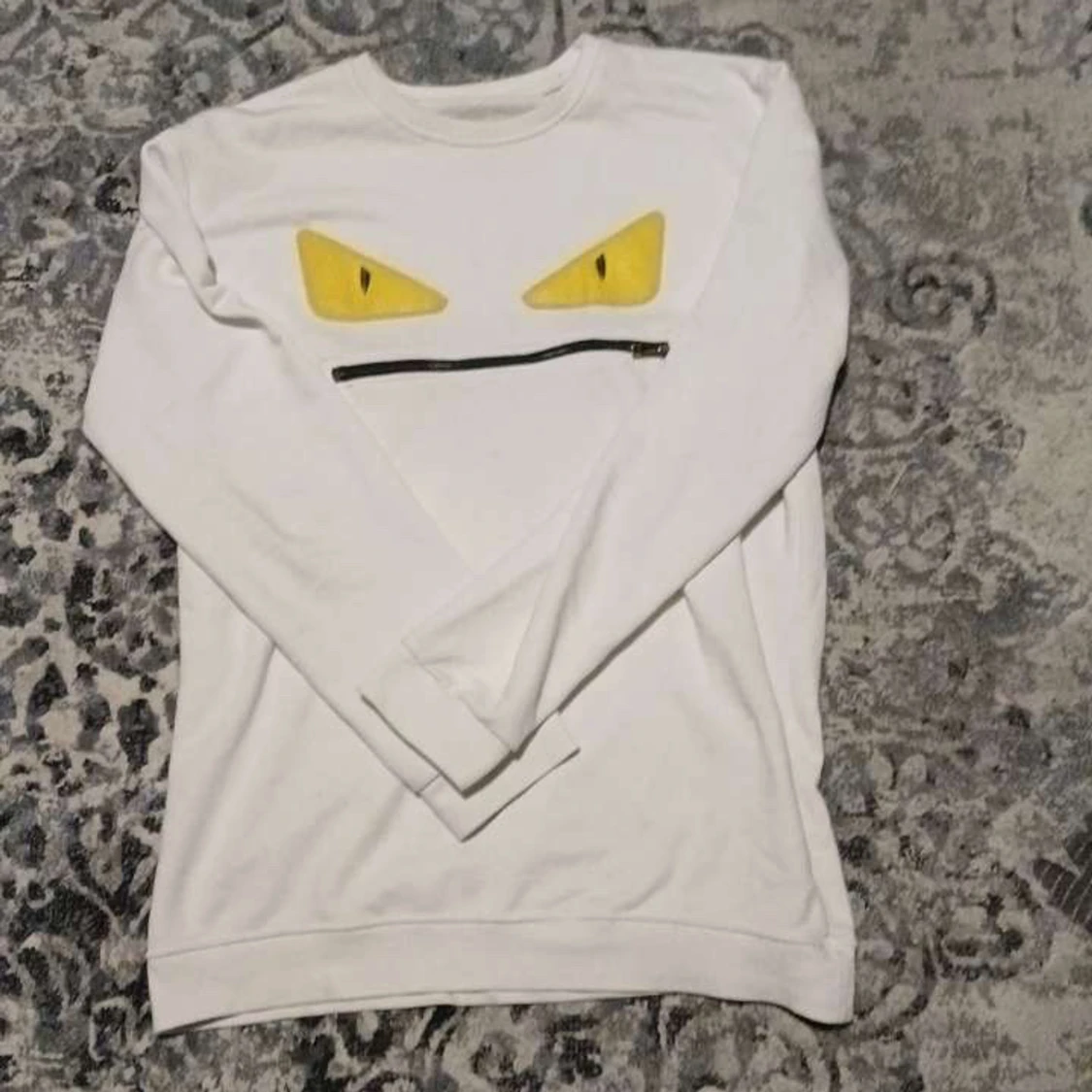 Vit tröja med gula ögon och dragkedja