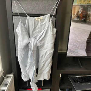 Ljusblå topp från Djerf Avenue - Säljer en stilren ljusblå knytblus från Djerf Avenue. Toppen har smala axelband och en elegant design som passar perfekt för varma dagar. Materialet känns mjukt och luftigt.