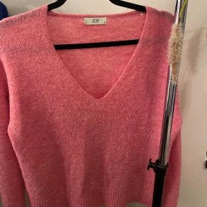 Rosa tröja från JDY - Säljer en mysig rosa tröja från JDY med v-ringning. Tröjan har långa ärmar och är perfekt för kyligare dagar. Den är mjuk och bekväm att bära. Den är stor i formen så den kan passa ända till storlek M skulle jag säga. Den är använd ett par gånger.💓