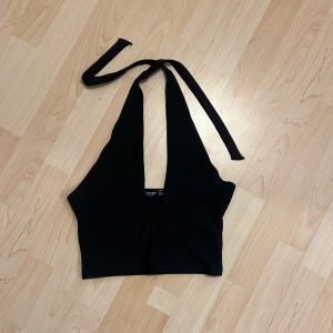 Svart halterneck topp från Stradivarius - Snygg svart halterneck topp från Stradivarius. Perfekt för en stilren look med knytband runt halsen. 