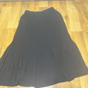 Svart plisserad kjol - Elegant svart plisserad kjol med en flytande design. Perfekt för en stilren look. Kjolen har en elastisk midja för bekväm passform. Priset går att diskuteras 