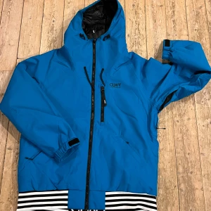 Blå vindjacka från CLWR - Helt oanvänd snygg blå vindjacka från CLWR med huva och dragkedja framtill. Nypris: 1200kr. Jackan har svarta detaljer och elastiska muddar. Perfekt för blåsiga dagar.