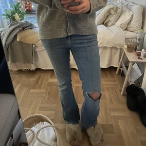 Bootcut jeans med slitningar - Snygga blå bootcut jeans med slitningar på knäna. De har en klassisk femficksdesign och en bekväm passform. Perfekta för en avslappnad stil. Det är zaras gamla och trendiga jeans som jag själv klippt hål i så därför inte ”perfekt” hål. Den har som en liten slitning vid fickan på baksidan som jag själv sytt ihop igen men inget jag tycker märks av specielt inte om man har en lite längre tröja. 