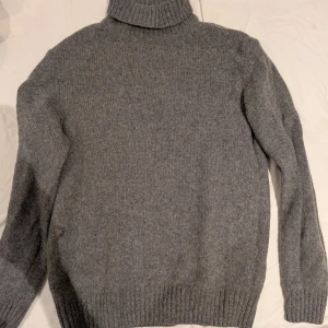 Grå stickad polotröja från Zara i M - Säljer en stilren grå stickad polotröja med ribbstickade detaljer vid ärmslut och nederkant. Från Zara i stl M.