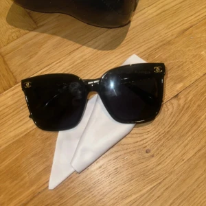 Svarta solglasögon med gulddetaljer - Snygga svarta solglasögon med fyrkantig form och eleganta gulddetaljer vid gångjärnen. Perfekta för en stilren look.